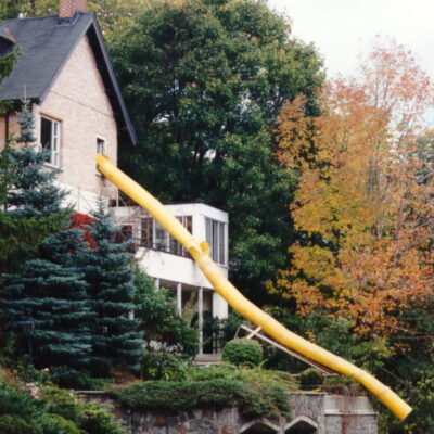 Yellow Superchute transporting construction debris downhill from a house.